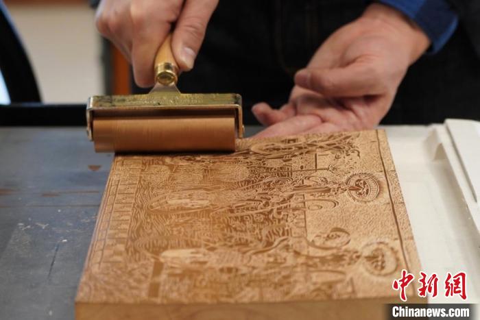 圖為徐晉林工作室工作人員正在給雕好壁畫的版面滾油墨?！【琶赖┰?　攝