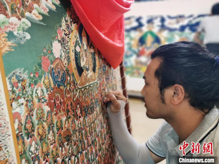 圖為更登才讓的徒弟繪畫(huà)唐卡?！?zhí)砀?攝
