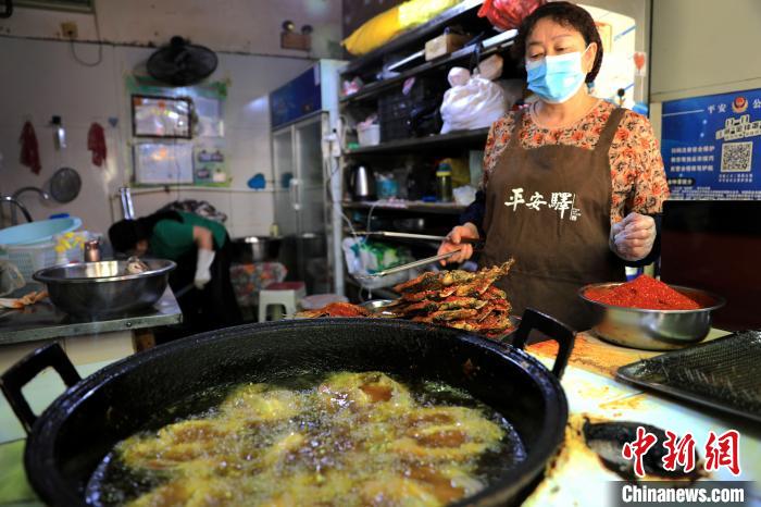 圖為平安驛·河湟民俗文化體驗(yàn)地內(nèi)的商戶炸干板魚?！⊙Φ?攝